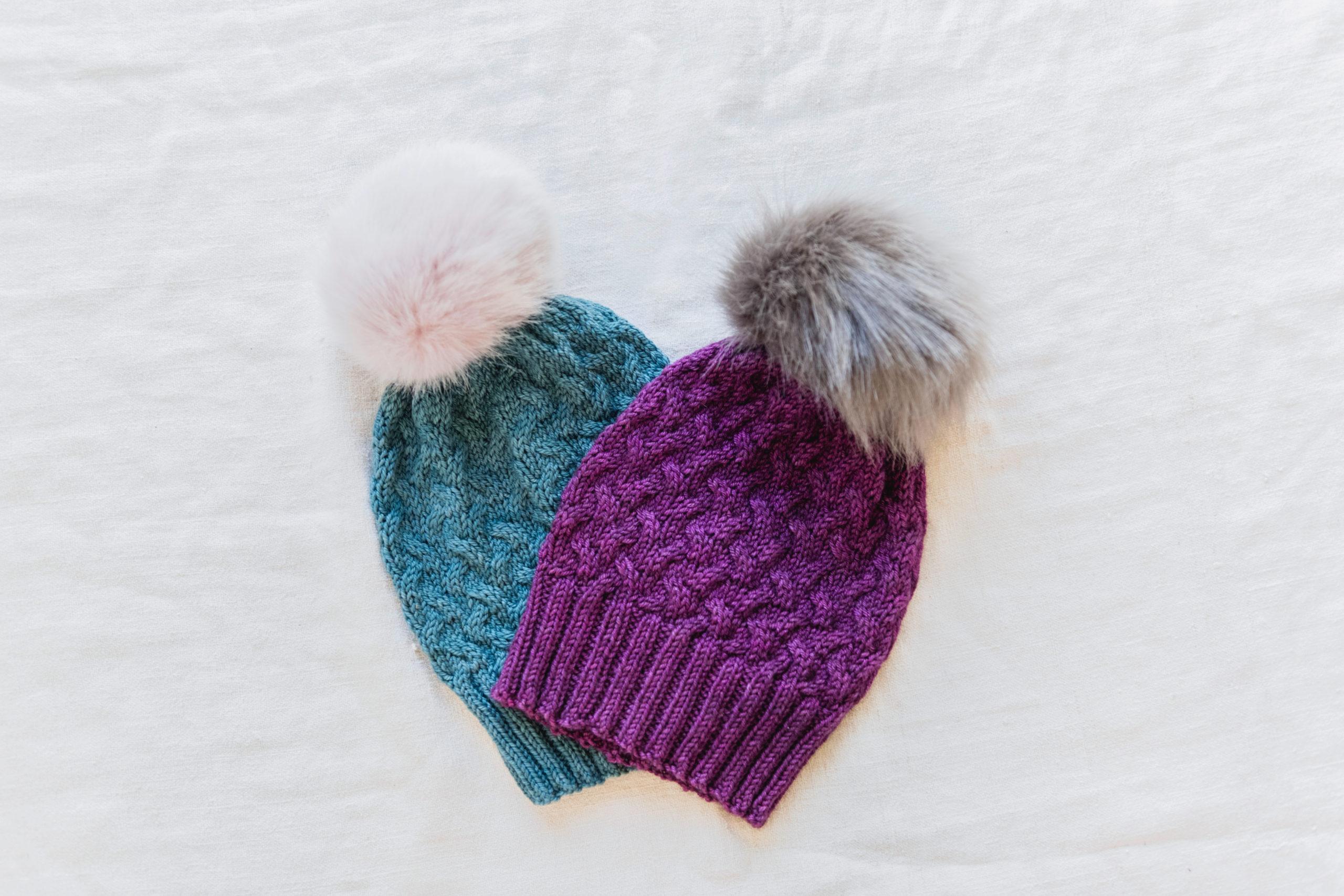 A green and purple knit bobble hat with a fluffy fur-like bobble