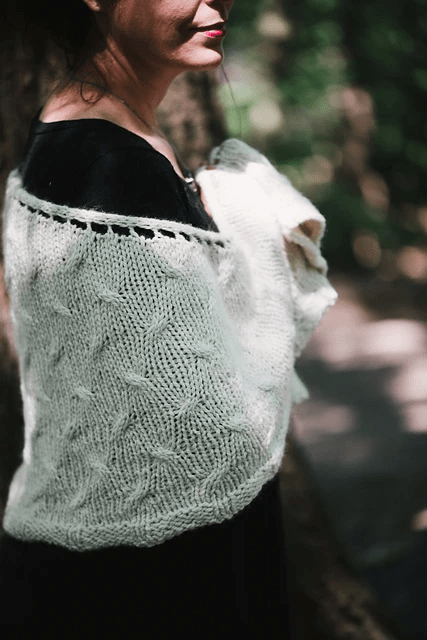 Helen Stewart stands to the side, wearing a white elegant hand-knit shawl with a raised stitch pattern.