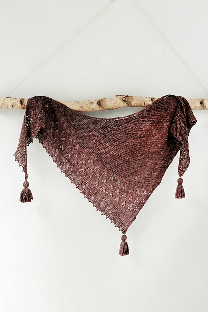 A brown triangle finely knitted shawl with a simple lace panel and tassels on the corners.