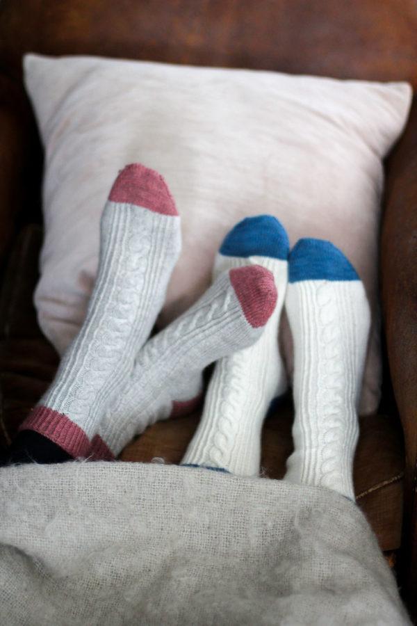 A couple wearing white socks, one with pink top, heel and toe patches and another with blue top, heel and toe patches.