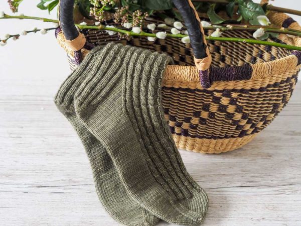 The Curling Mist Socks are a moss green knit, from the top-down with tiny cables and continue all over the leg and onto the top of the foot.