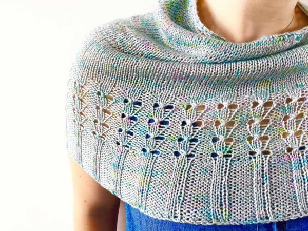 Fireflies Rising Shawl is pale blue with flects of yellow, green and pink throughout