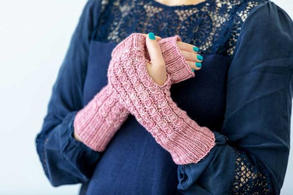The Homebody Mitts are pink wristwarmers, or armwarmers, with mock cable stitch pattern and ribbing work