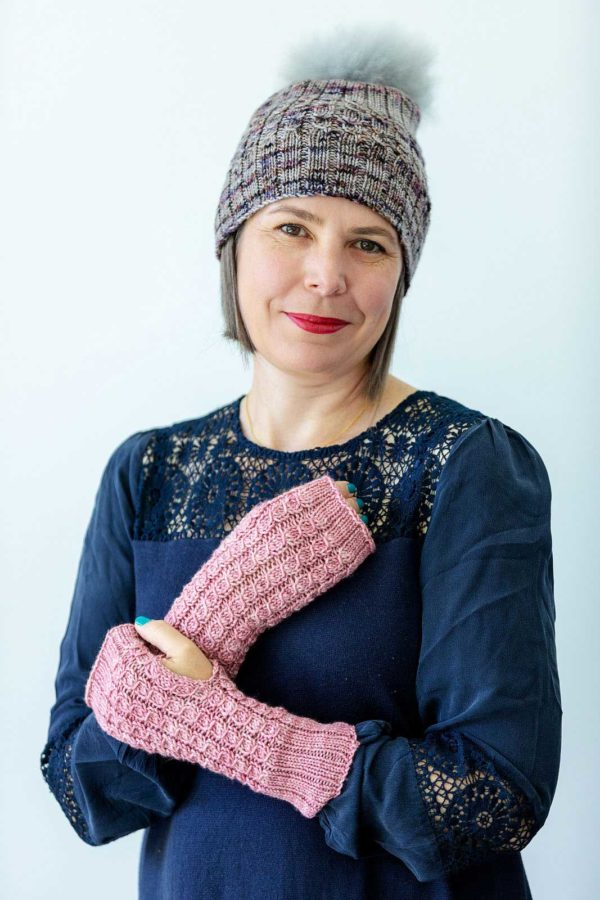 The Homebody Mitts are pink wristwarmers, or armwarmers, with mock cable stitch pattern and ribbing work
