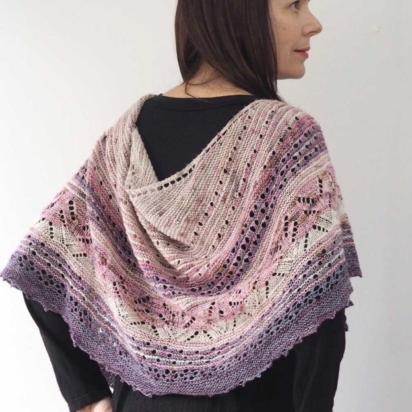 A multi-coloured artistic shawl, starting with creams and pinks and light to darker purples at the bottom of the shawl