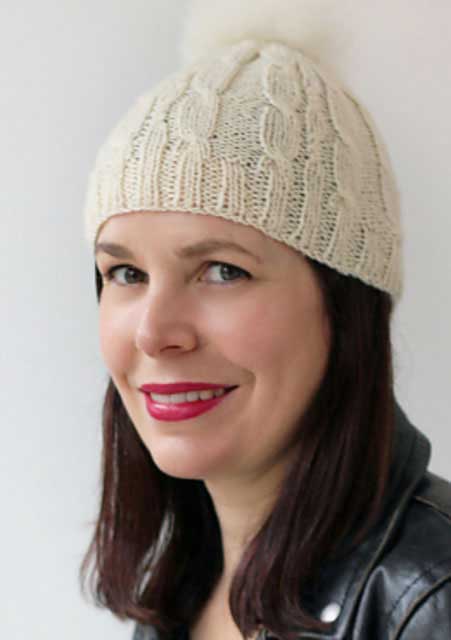 The Kindling Hat in cream with a fluffy white bobble on top.