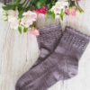 The Lavender Fields Socks are knit from the top down with a lavender-inspired lace panel around the top of the leg.