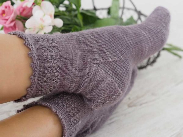 The Lavender Fields Socks are knit from the top down with a lavender-inspired lace panel around the top of the leg.