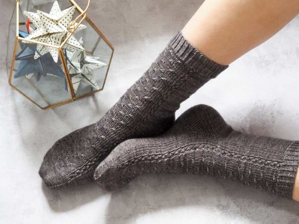 The Luminary socks with cables runs along the front and top of the foot, and relaxing stockinette on the back of the leg.