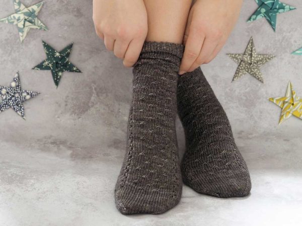 The Luminary socks with cables runs along the front and top of the foot, and relaxing stockinette on the back of the leg.
