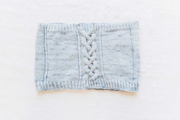 The Rose Cottage Cowl is a gentle knit, it features a braid cable panel against a stockinette stitch for a modern twist on a traditional design motif.