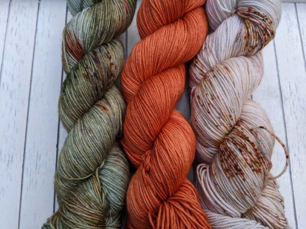 Twisted Yarns in vibrant orange, speckled pale green with oraneg and white, and the last yarn is a speckled cream and orange
