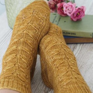 The Wild Bees Socks pattern features three sizes, a bee-inspired lace panel travels down the front of the leg and the top of the sock, ending with a pretty eye of partridge heel and a round toe.