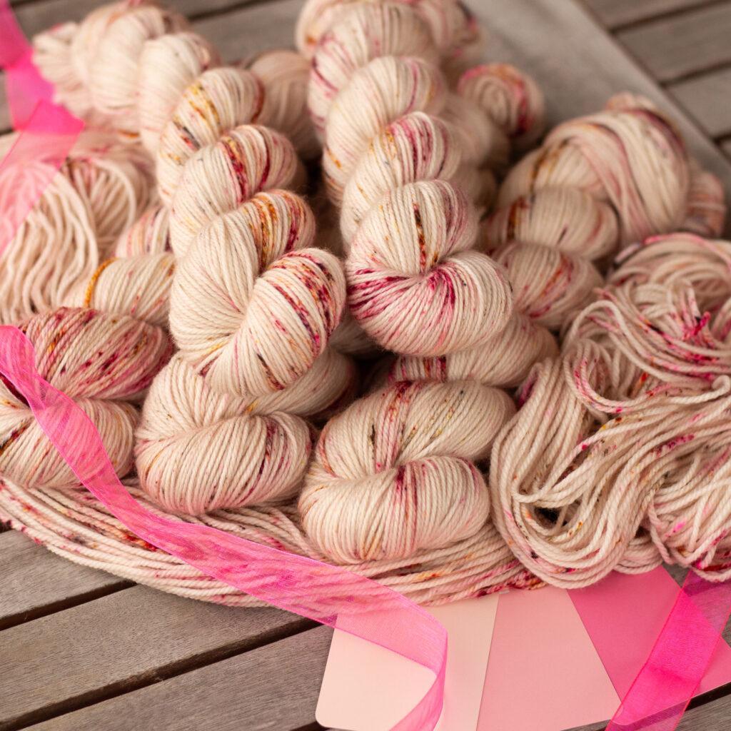 A basket filled with skeins of pink and cream speckled yarn