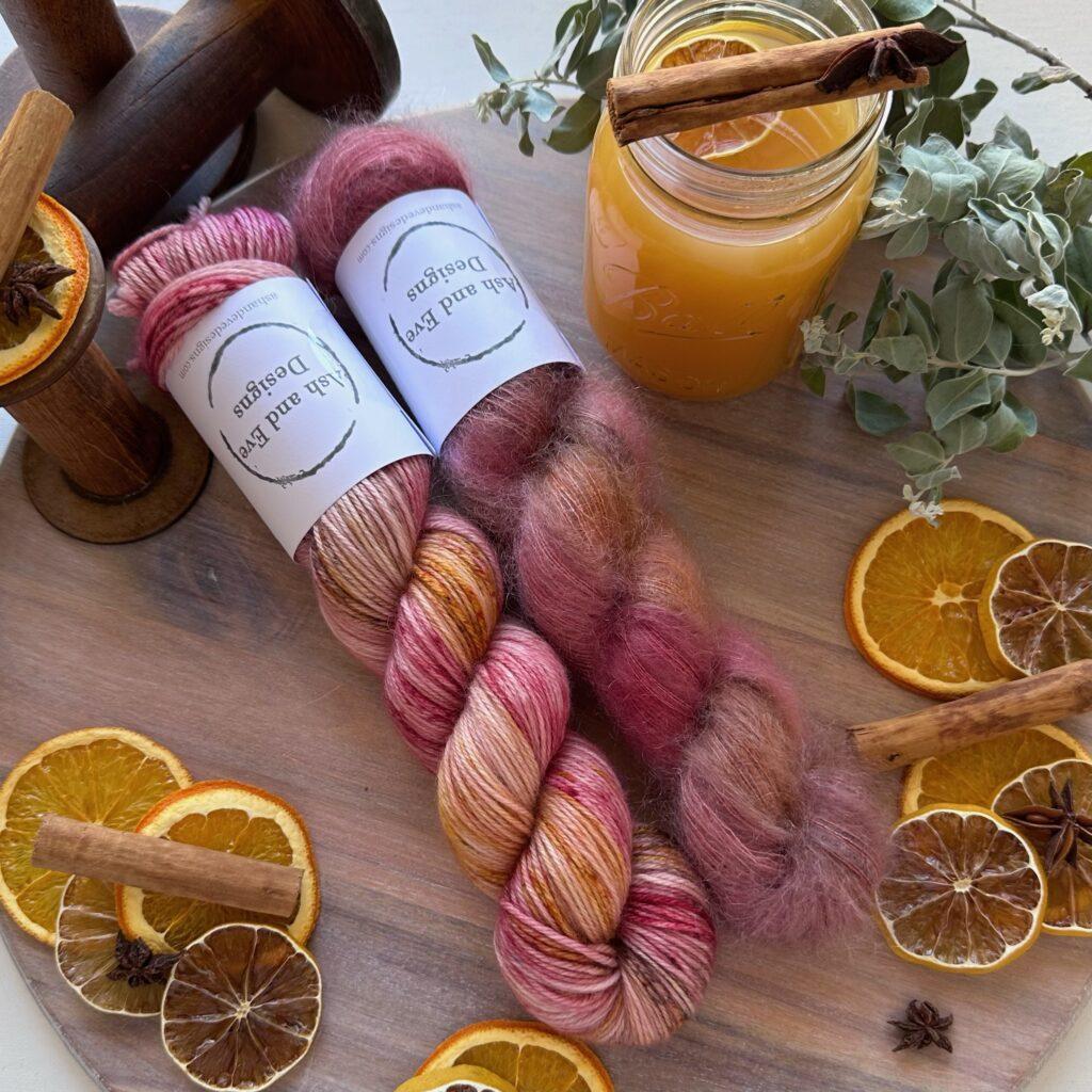 Two skeins of hand dyed yarn surrounded by orange slices and cinnamon sticks