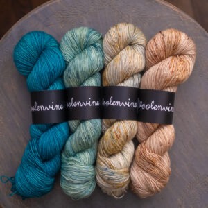 Four skeins of hand dyed yarn in a row, from let to write a teal, a light green, a light gold and a light peach