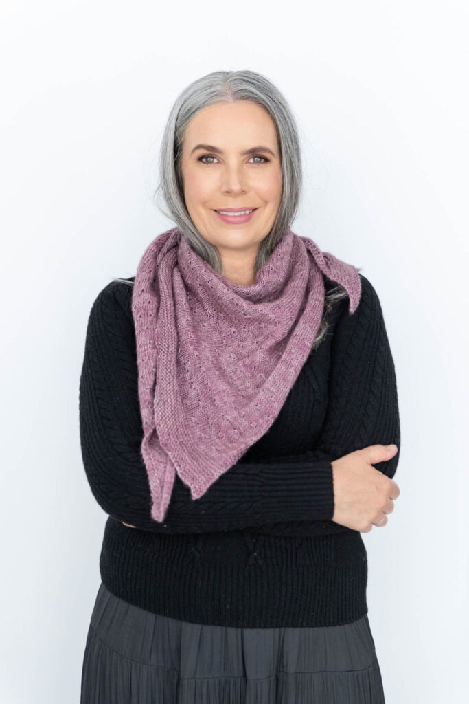 Helen wearing a pink triangle shawl around her neck, smiling at the camera