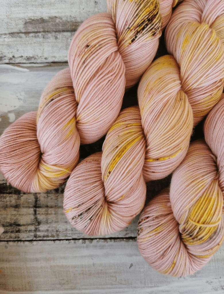 Three skeins of pink speckled sock yarn